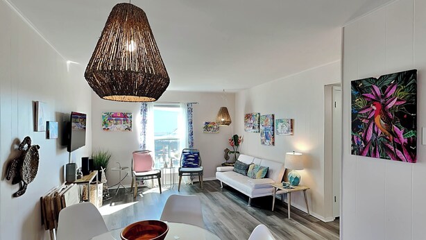Un salon moderne avec une table à manger en verre, des canapés blancs et un grand luminaire suspendu.