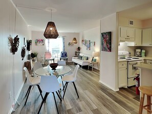 Een moderne woonruimte met een eethoek, een bank, een keuken en een groot raam.