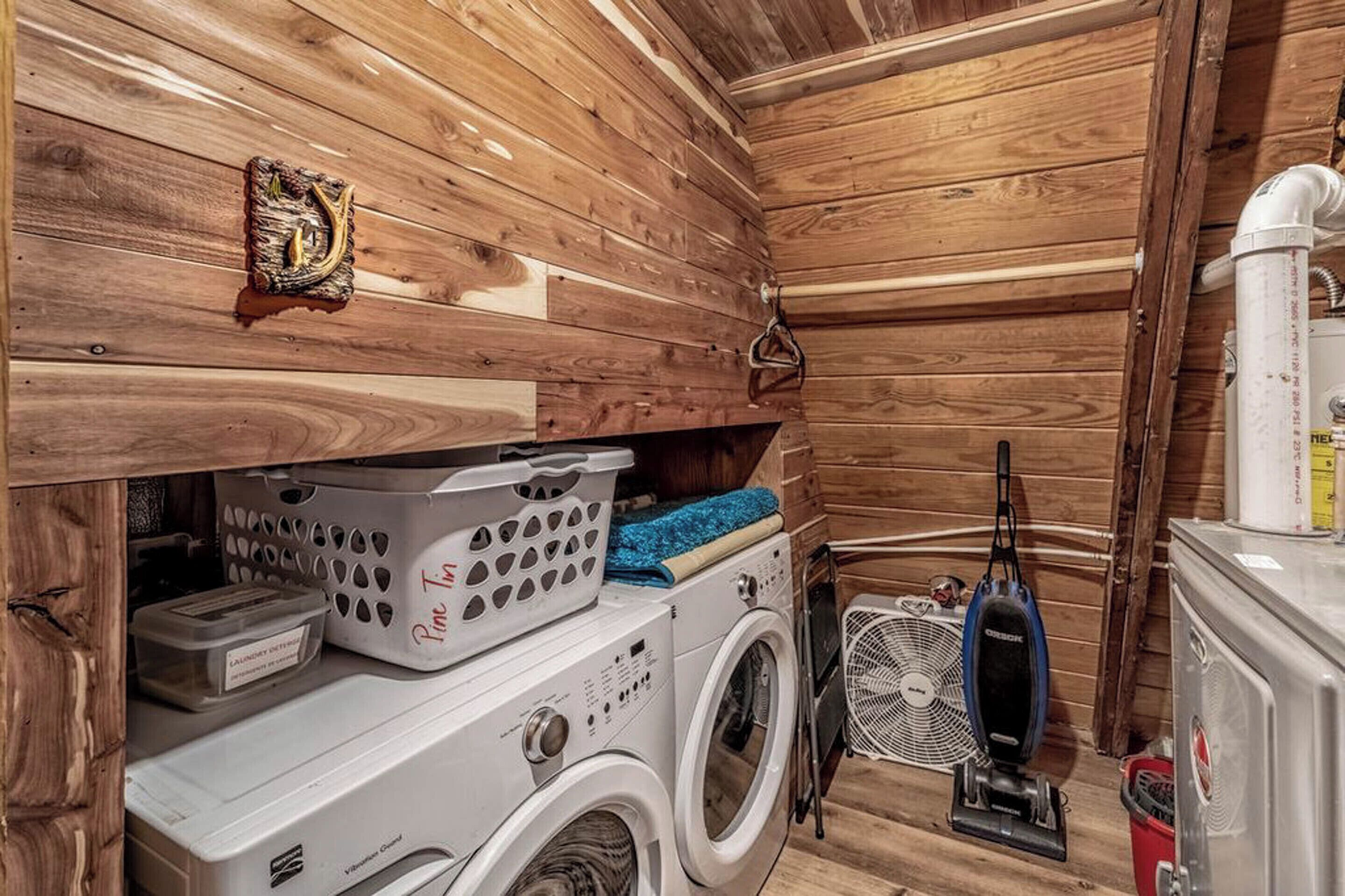 A compact laundry room with a washing machine, dryer, and vacuum cleaner.