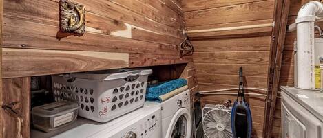A compact laundry room with a washing machine, dryer, and vacuum cleaner.