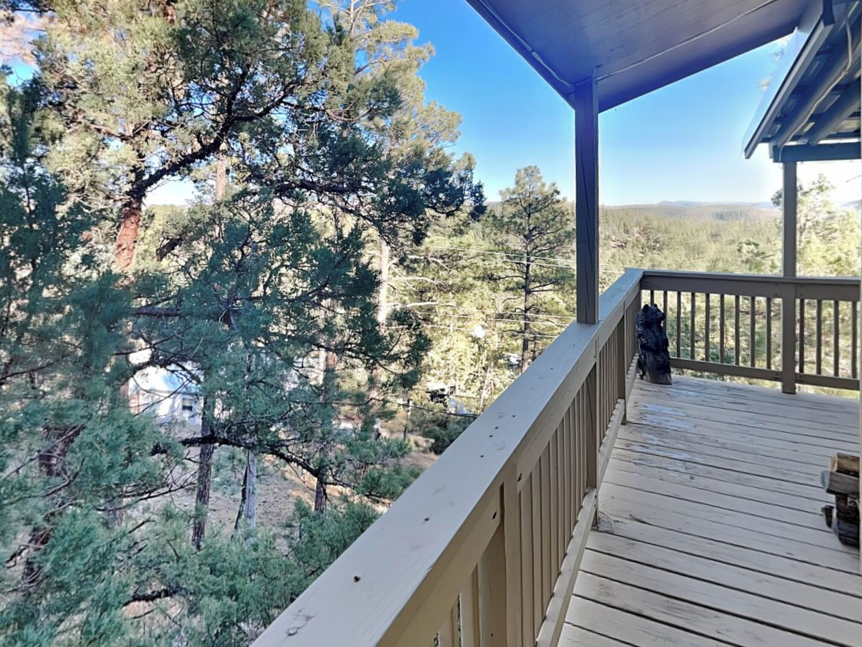 A wooden deck with a railing overlooking a forested area.