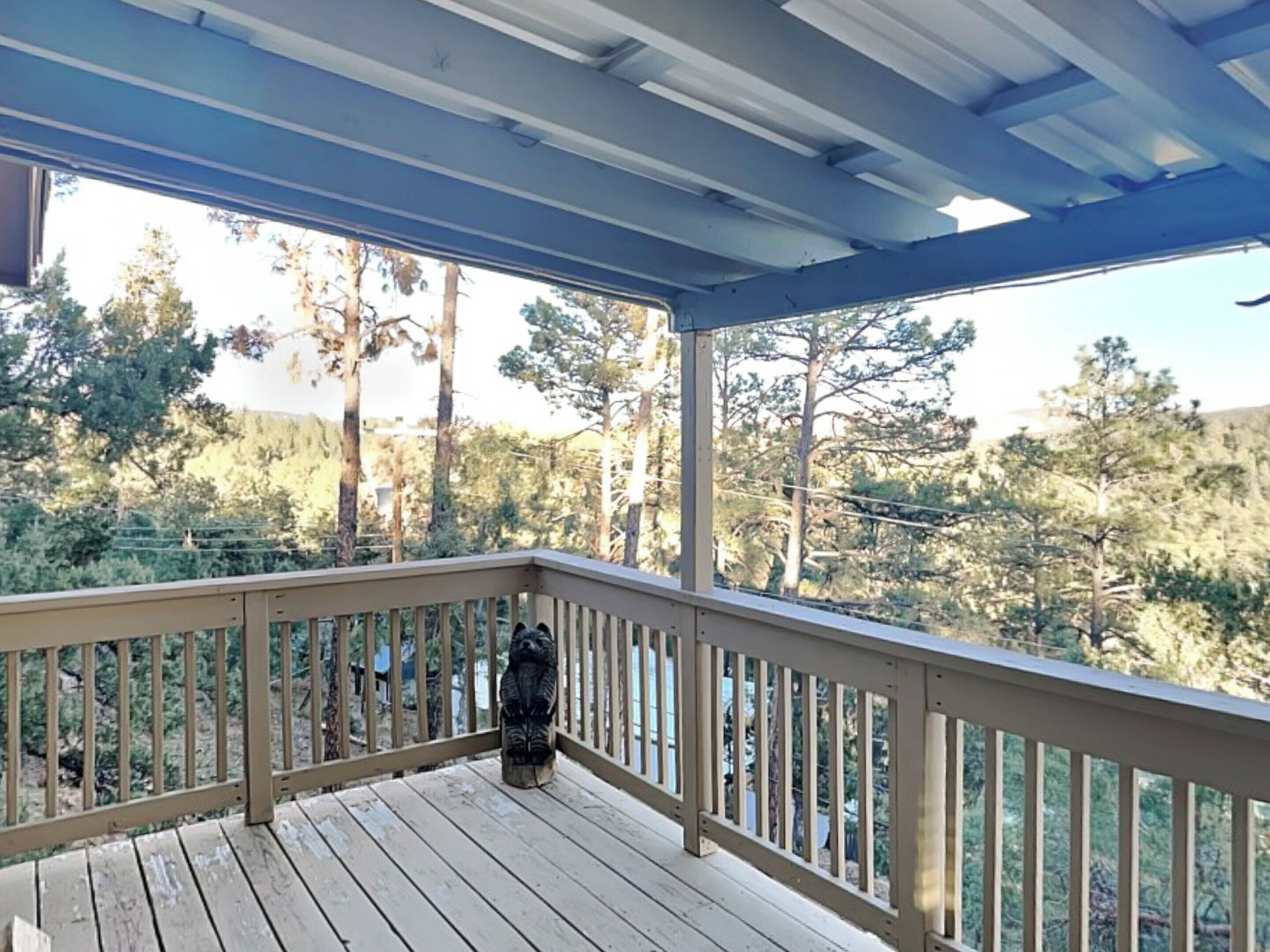 Una terraza de madera con barandilla, con vista a un área boscosa.