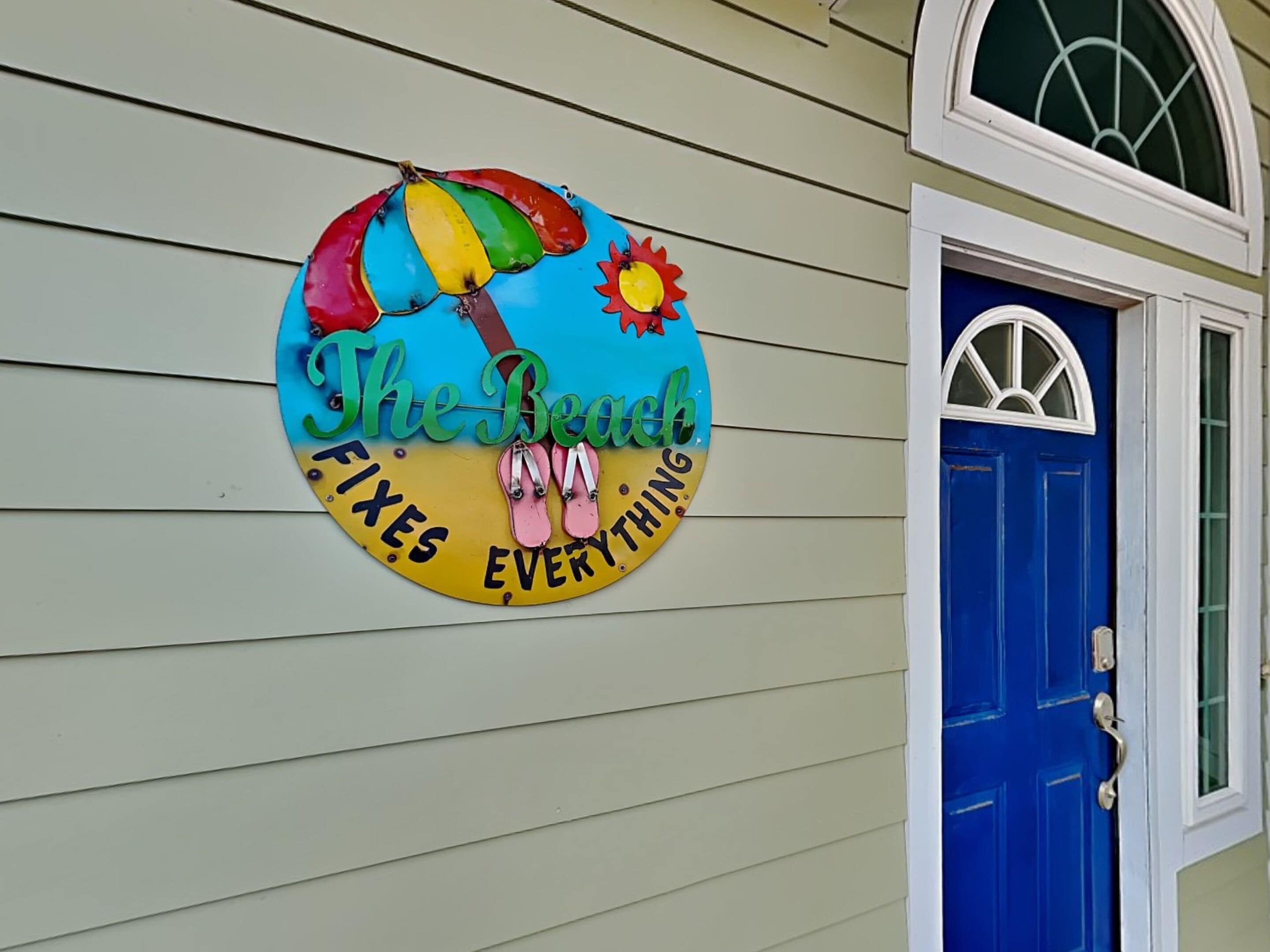 Une affiche colorée sur le mur d’une maison fait la publicité de l’endroit suivant : « La plage, la solution à tous les problèmes ».