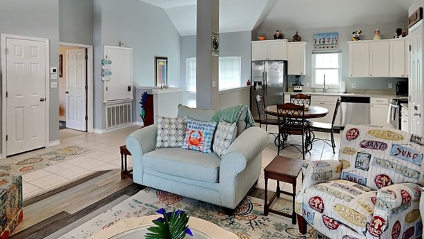 A spacious living room with a light blue sofa, a coffee table with magazines, and a patterned rug. - Beach Place by Silver Sands Vacation Rentals (Port Aransas)