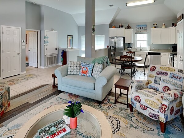 A spacious living room with a light blue sofa, a coffee table with magazines, and a patterned rug. - Beach Place by Silver Sands Vacation Rentals (Port Aransas)