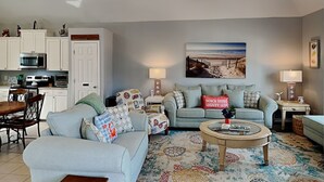 A living room with a sofa, coffee table, and patterned rug. - Beach Place by Silver Sands Vacation Rentals (Port Aransas)