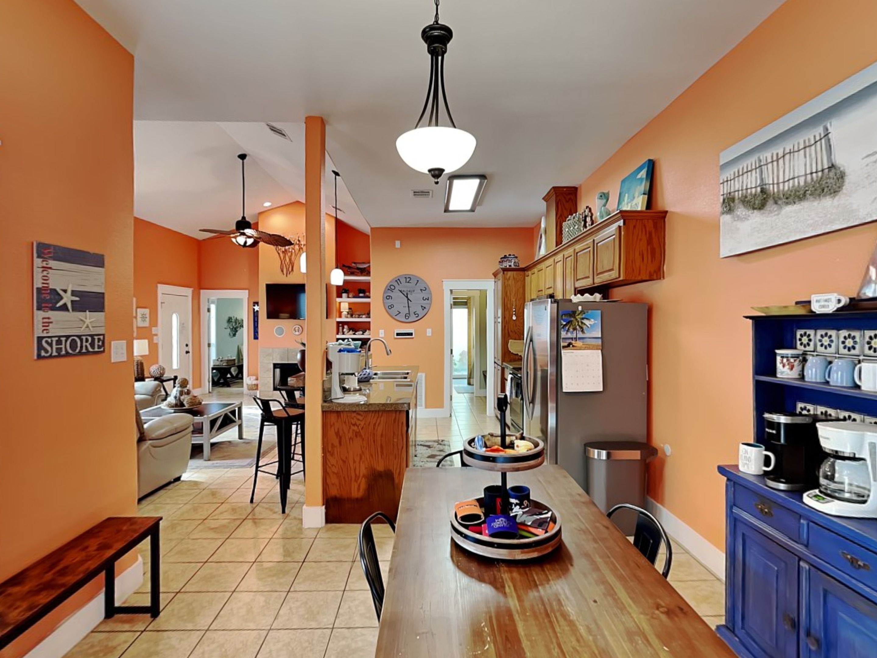 A spacious kitchen with wooden cabinets, a dining area with a bench, and a clock on the wall.