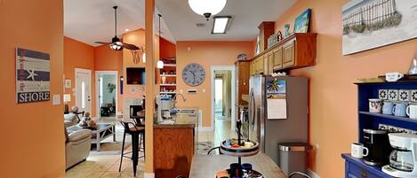 A spacious kitchen with wooden cabinets, a dining area with a bench, and a clock on the wall.