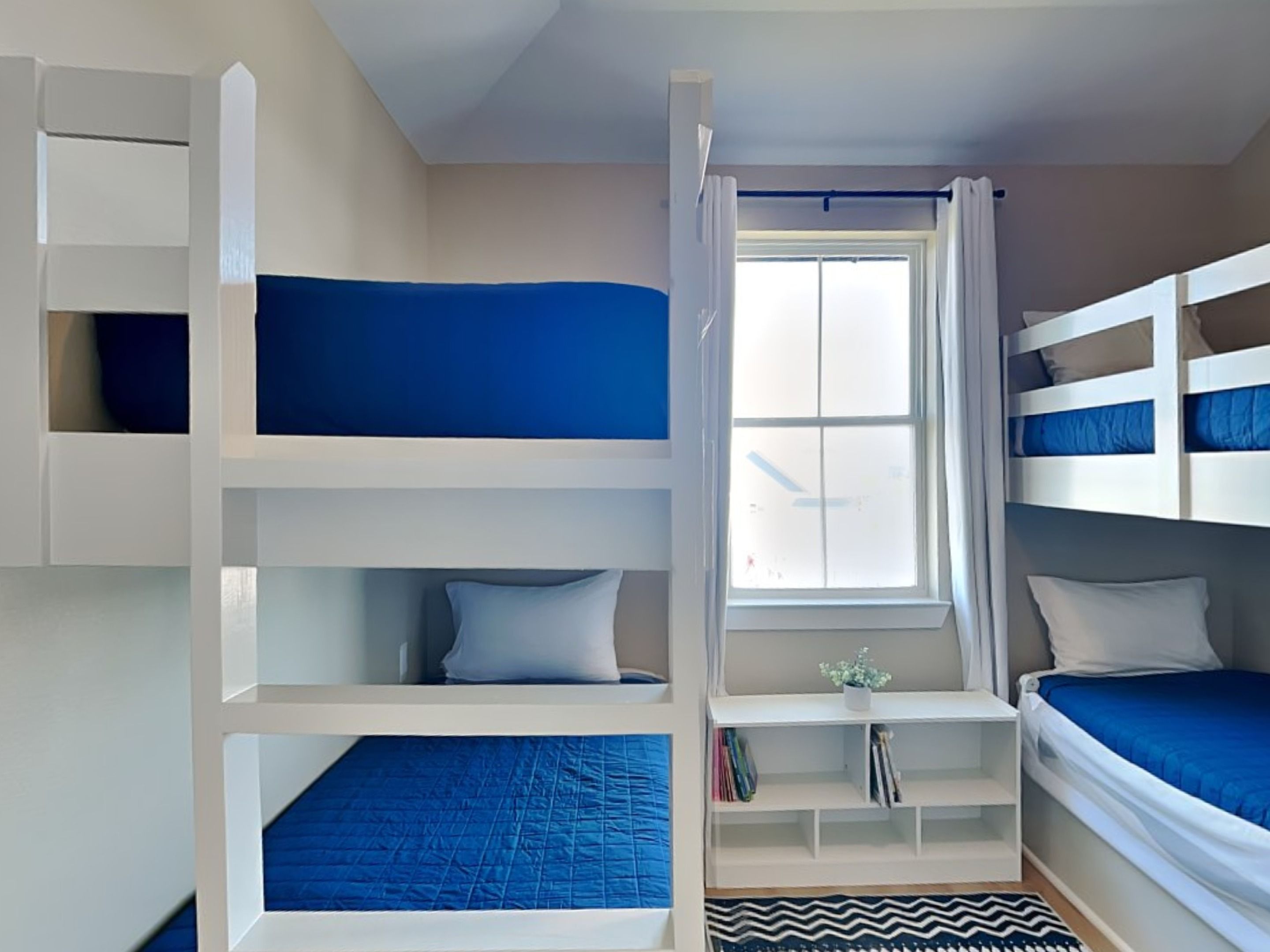 A bedroom with bunk beds, a window, and built-in shelving.