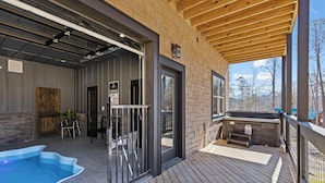 A wooden deck with a hot tub, a pool, and a covered seating area. - S'more Splashing by Smoky Cove Resort (Sevierville)