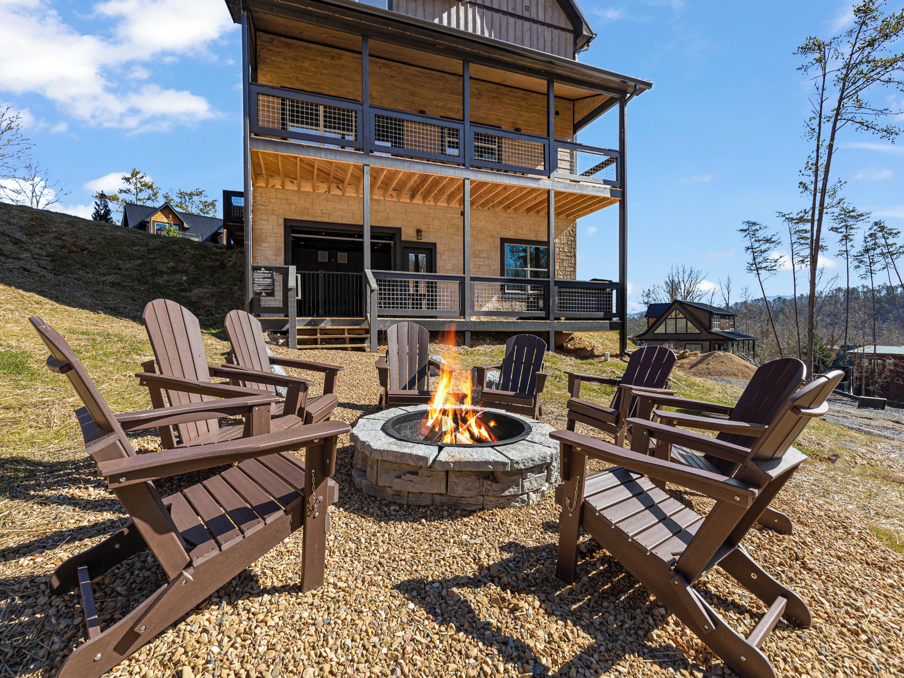 A two-story building with a fire pit and Adirondack chairs in front.