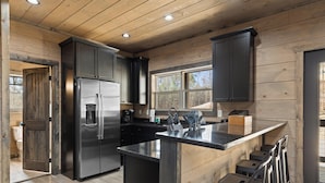 A modern kitchen with a stainless steel refrigerator, black cabinets, and a wooden ceiling. - S'more Splashing by Smoky Cove Resort (Sevierville)
