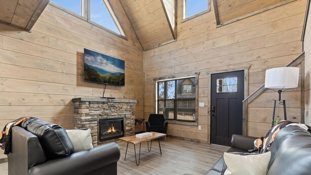 A cozy living room with a fireplace, leather sofas, and a stone fireplace surround. - S'more Splashing by Smoky Cove Resort (Sevierville)