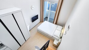 A modern hotel room with a bed, a desk, a flat-screen TV, and a view of the city. - Chuncheon Bella Residence Hotel (Chuncheon)