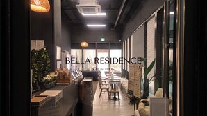 A modern interior with a reception desk, seating area, and a view of the outside. - Chuncheon Bella Residence Hotel (Chuncheon)