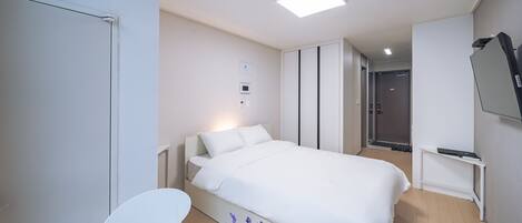 A modern hotel room with a large bed, a desk, and a TV.