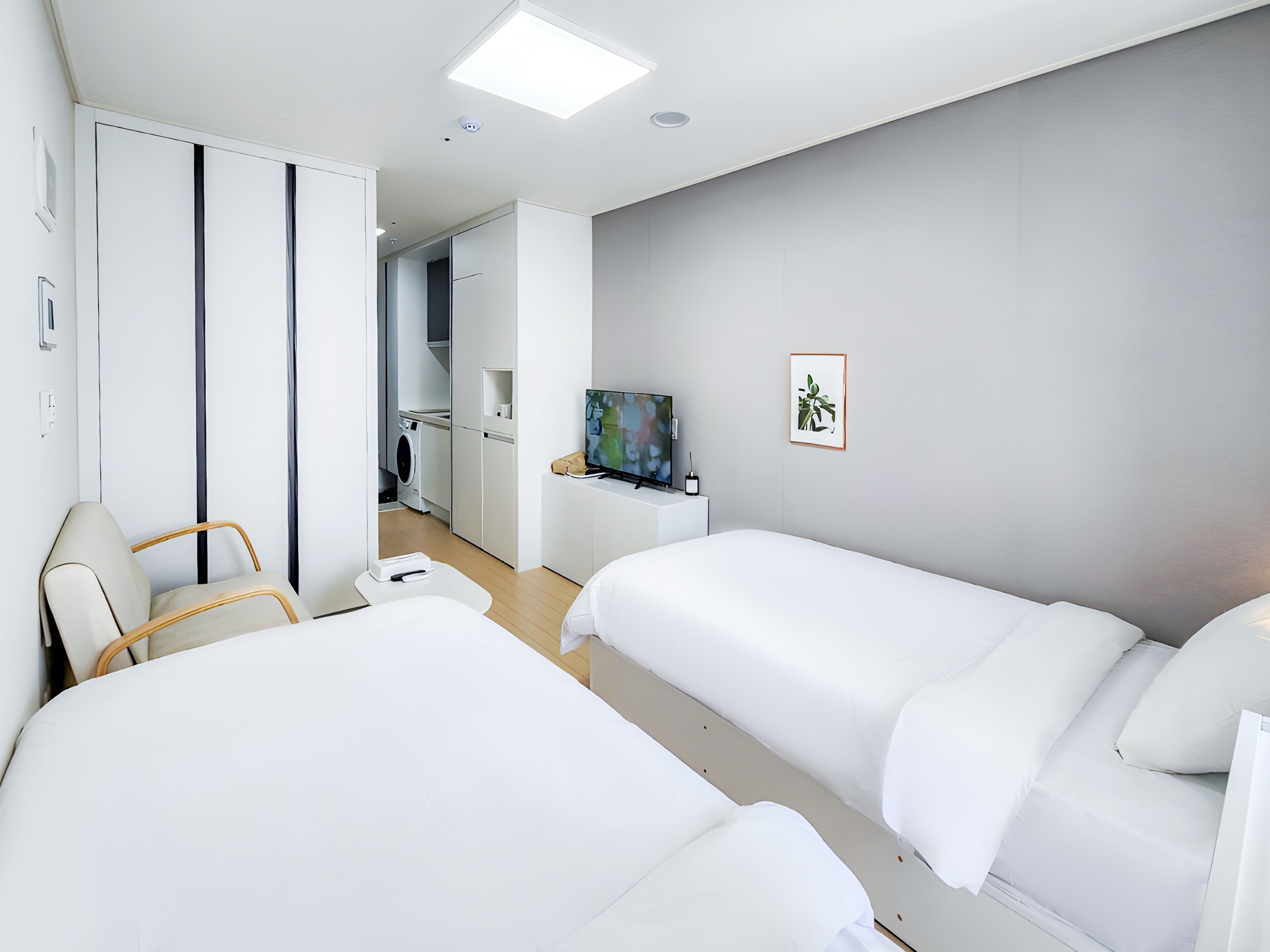 Una habitación de hotel moderna con dos camas, un televisor, un cuadro y un baño a la vista.