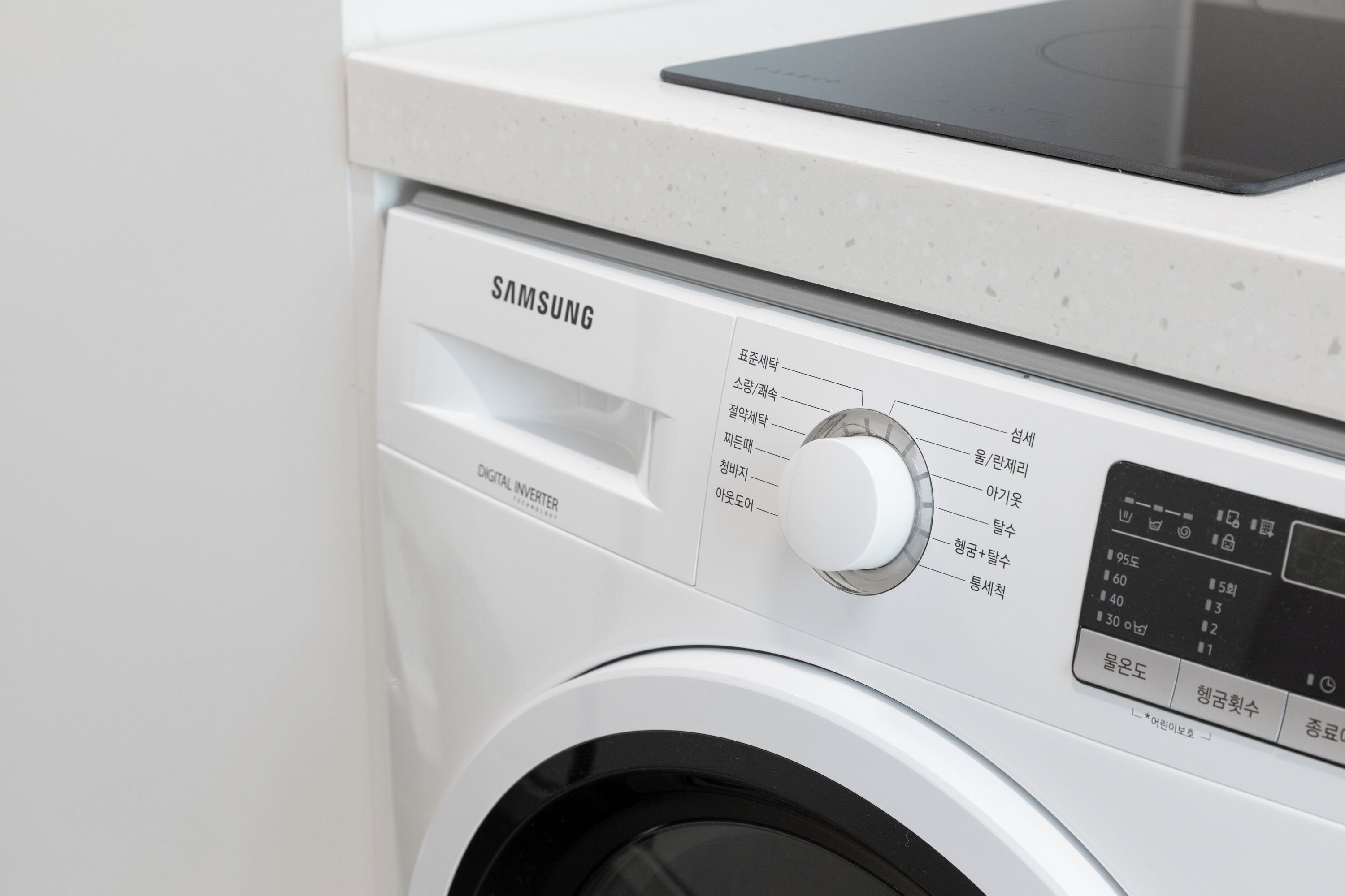A Samsung digital inverter washing machine with a control panel and a tablet on top.
