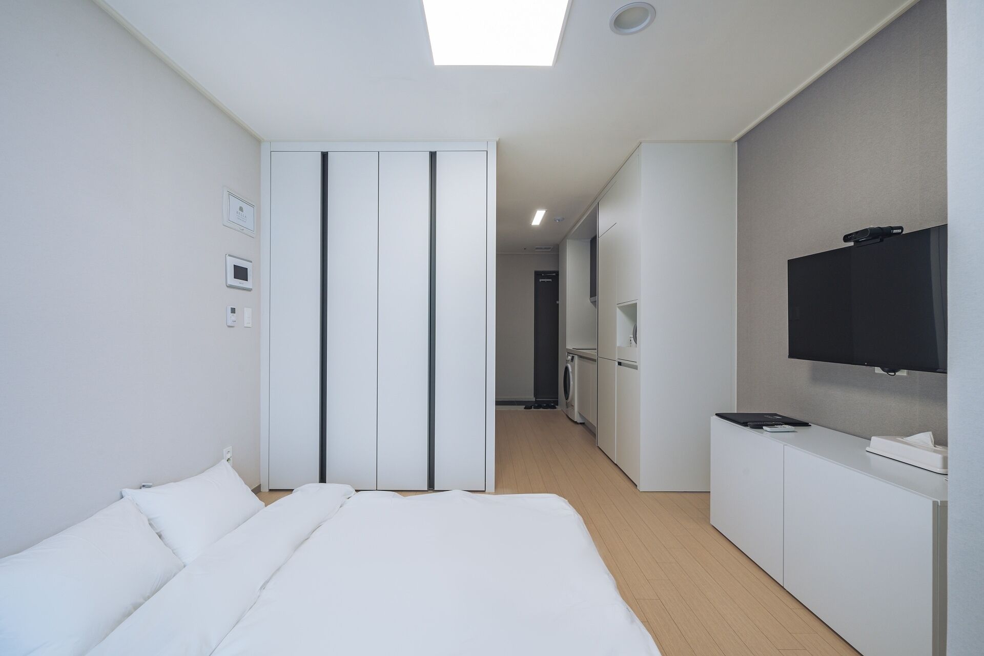 A modern hotel room with a large bed, a TV, a desk, and a wardrobe.