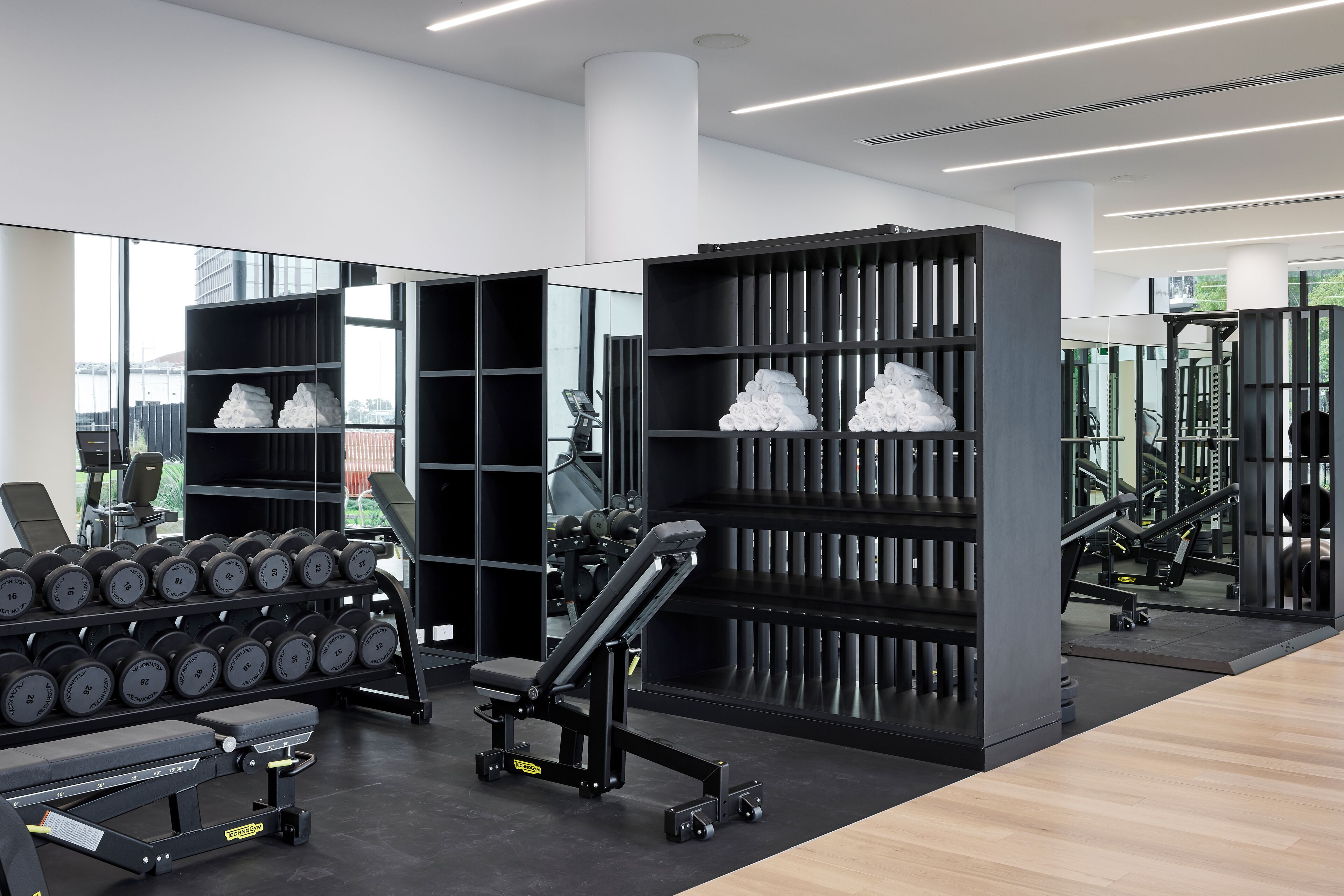 Ein modernes Fitnessstudio mit Kraftgeräten, Kurzhanteln und ordentlich gestapelten Handtüchern.