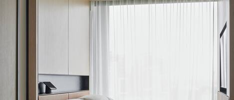 A minimalist bedroom with a bed, a small table, and a chair.