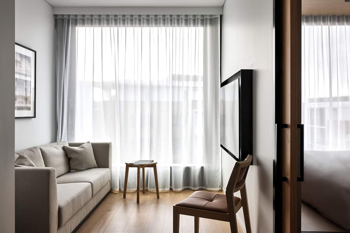 A modern living room with a sofa, a chair, a small table, and a TV mounted on the wall.