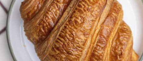 A croissant on a white plate with a grid-patterned tablecloth.