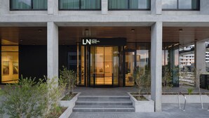 A modern hotel with a glass facade, a visible entrance, and a sign reading "LN HOTEL."