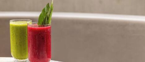 Dos vasos de batidos verdes y rojos sobre una superficie de mármol.