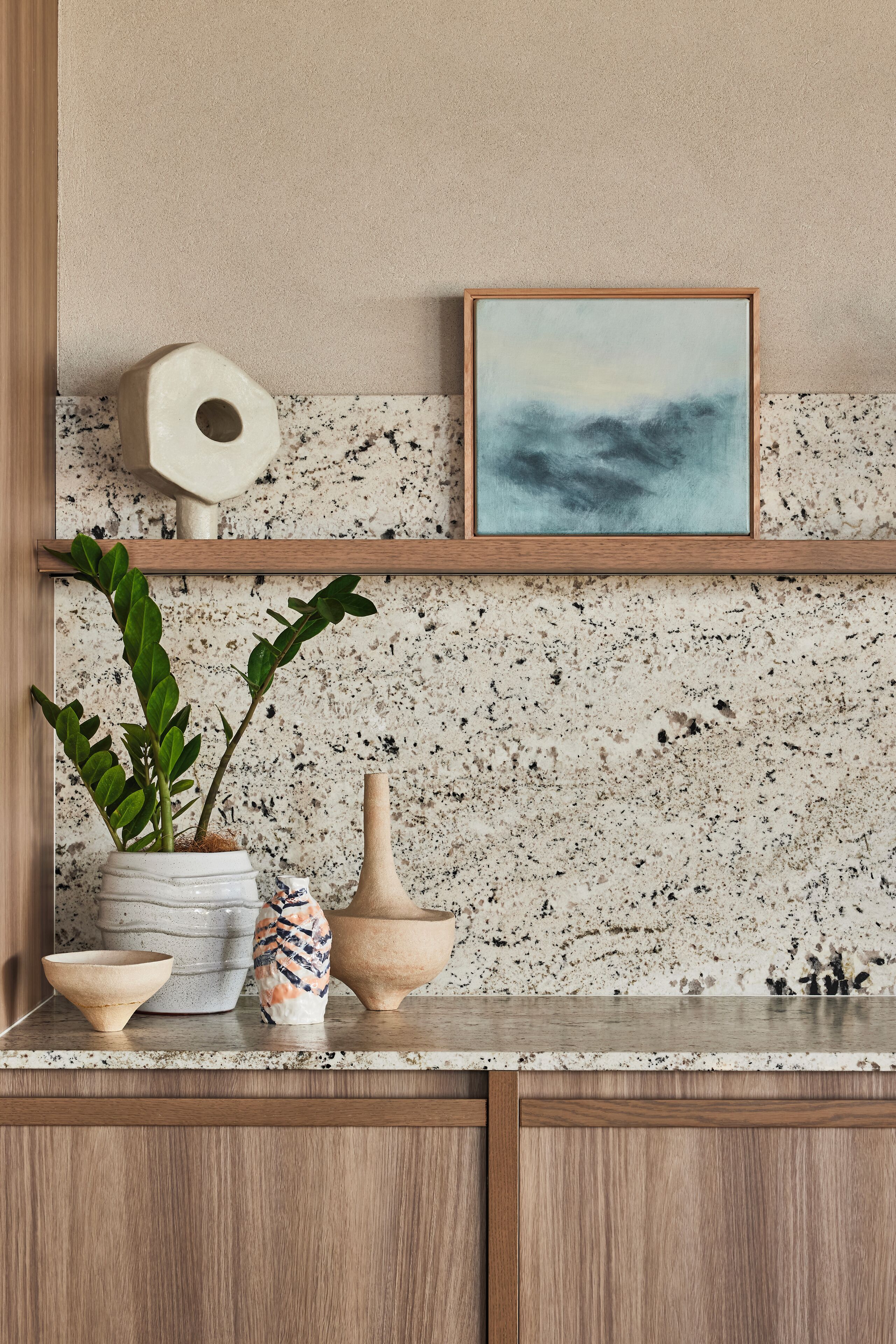 A kitchen counter with a potted plant, a bowl, and a vase.