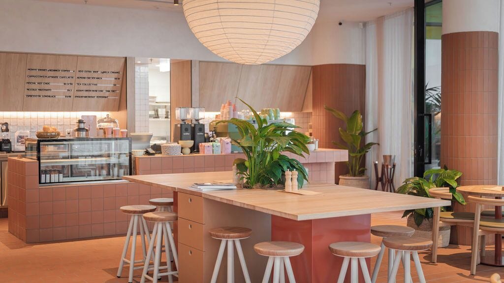 Un café moderne avec un îlot central, des tabourets de bar et un tableau affichant le menu.