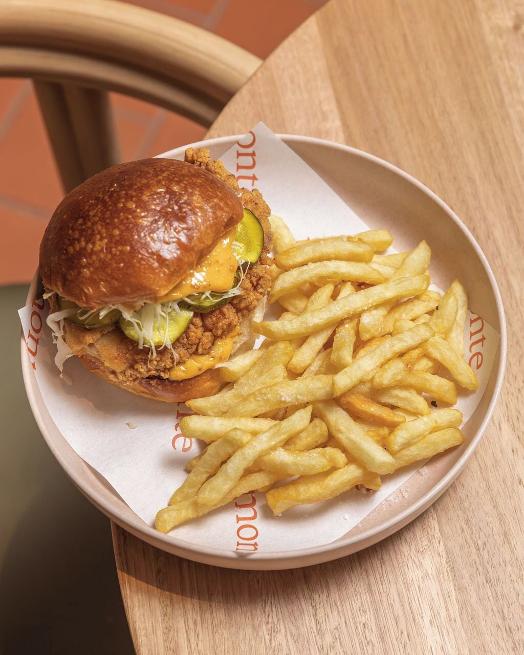 Un repas composé d’un hamburger et de frites, servi dans une assiette en papier.
