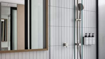 A modern bathroom with a white sink, a large mirror, and a glass-enclosed shower area.