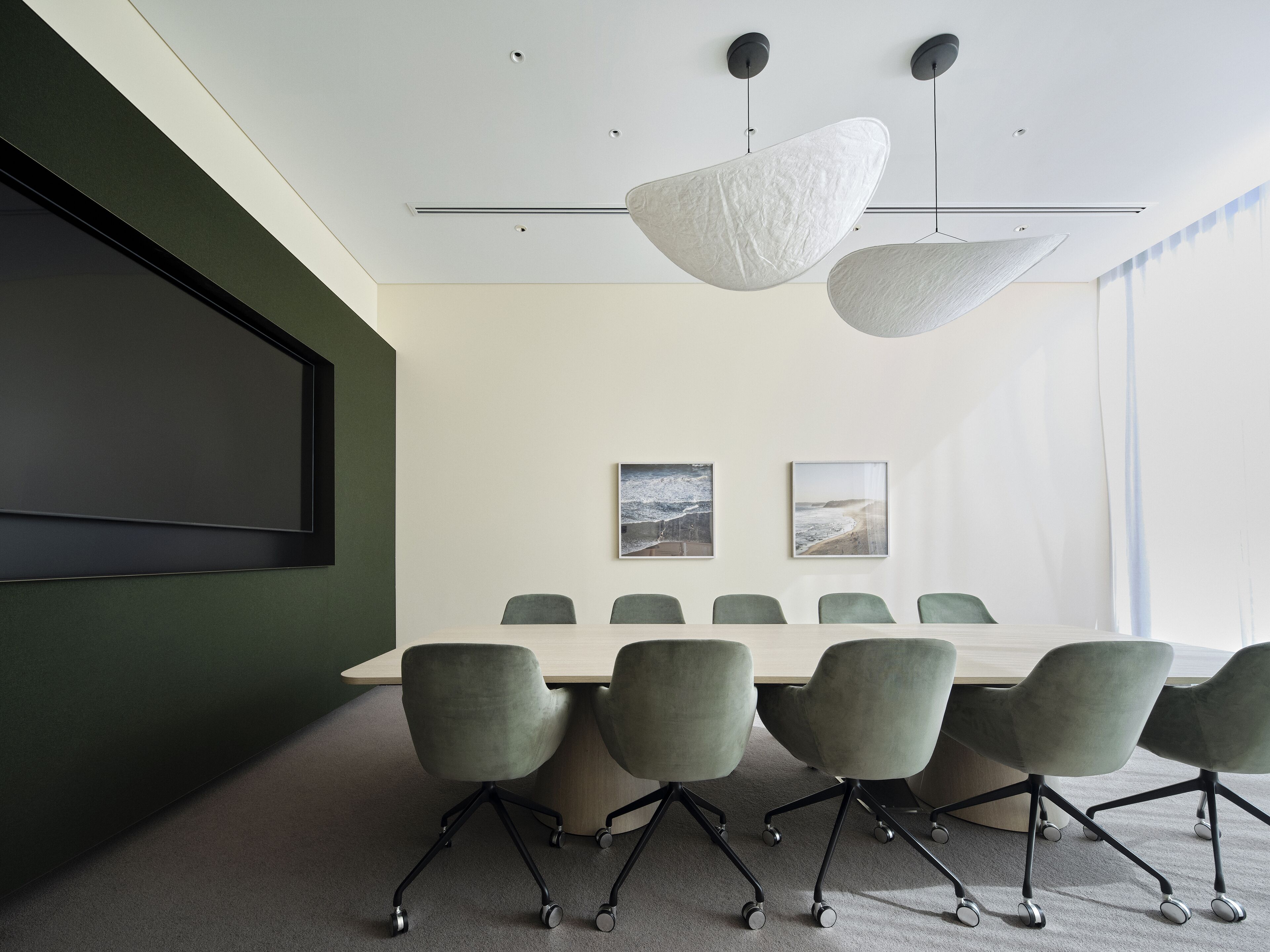 Une salle de conférence équipée d’une grande table, de six chaises et de deux luminaires fixés au mur.