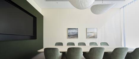 A conference room with a large table, six chairs, and two wall-mounted light fixtures.