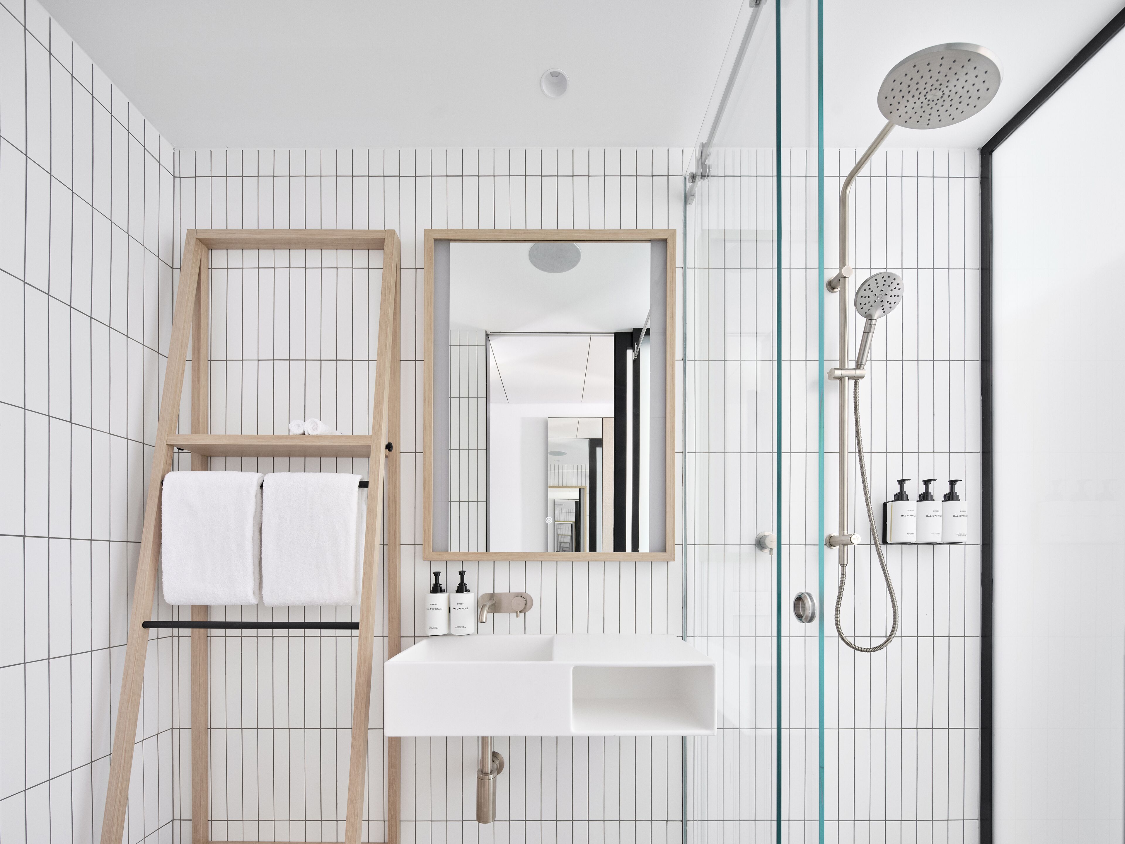 A modern bathroom with a wooden ladder, a mirror, a sink, and a shower.