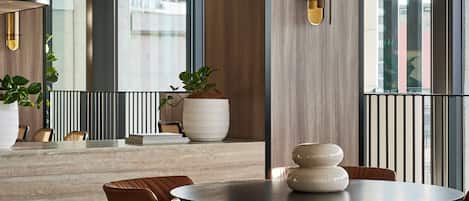 A modern dining area with a round table, brown chairs, and a large potted plant.