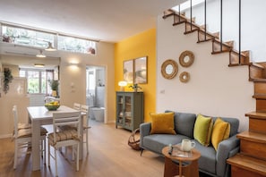 A modern living room with a staircase, a dining area, and a view of the outside.
