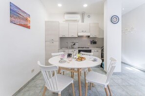 A modern kitchen with white cabinets, a round dining table with four white chairs, and a breakfast setting with croissants and coffee. - Nice apartment for 4 guests with WIFI, A/C (Viareggio)