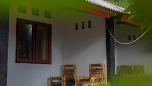 A room with a large window, a wall-mounted mirror, and two wooden chairs. - RR Homestay Kuta Lombok (Kuta)