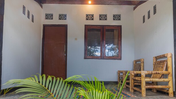 A wooden door, a window, and two wooden chairs outside a building. - RR Homestay Kuta Lombok (Kuta)