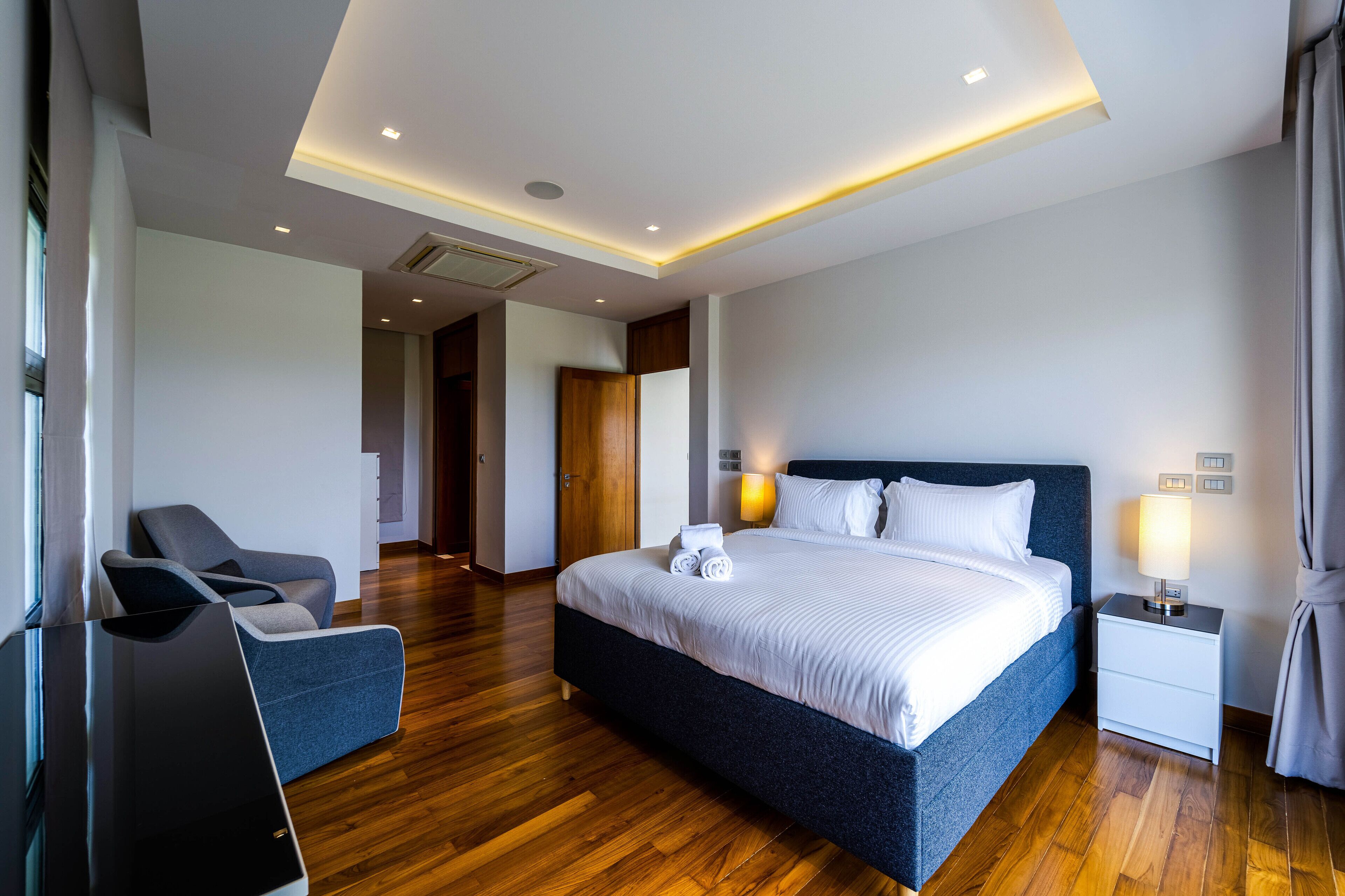 A modern hotel room with a large bed, bedside tables, a desk, and a chair.