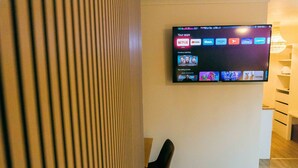 Une chambre moderne dotée d’un téléviseur à écran plat fixé au mur, qui permet d’accéder à diverses applications de diffusion en continu.