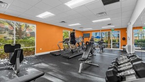 A gym with treadmills, weight benches, and dumbbells.