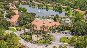 Vista aérea de un resort con un lago, palmeras y una piscina.