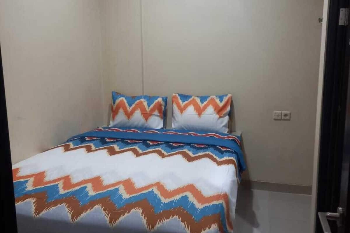 Un dormitorio con cama, dos almohadas y una mesita de noche.