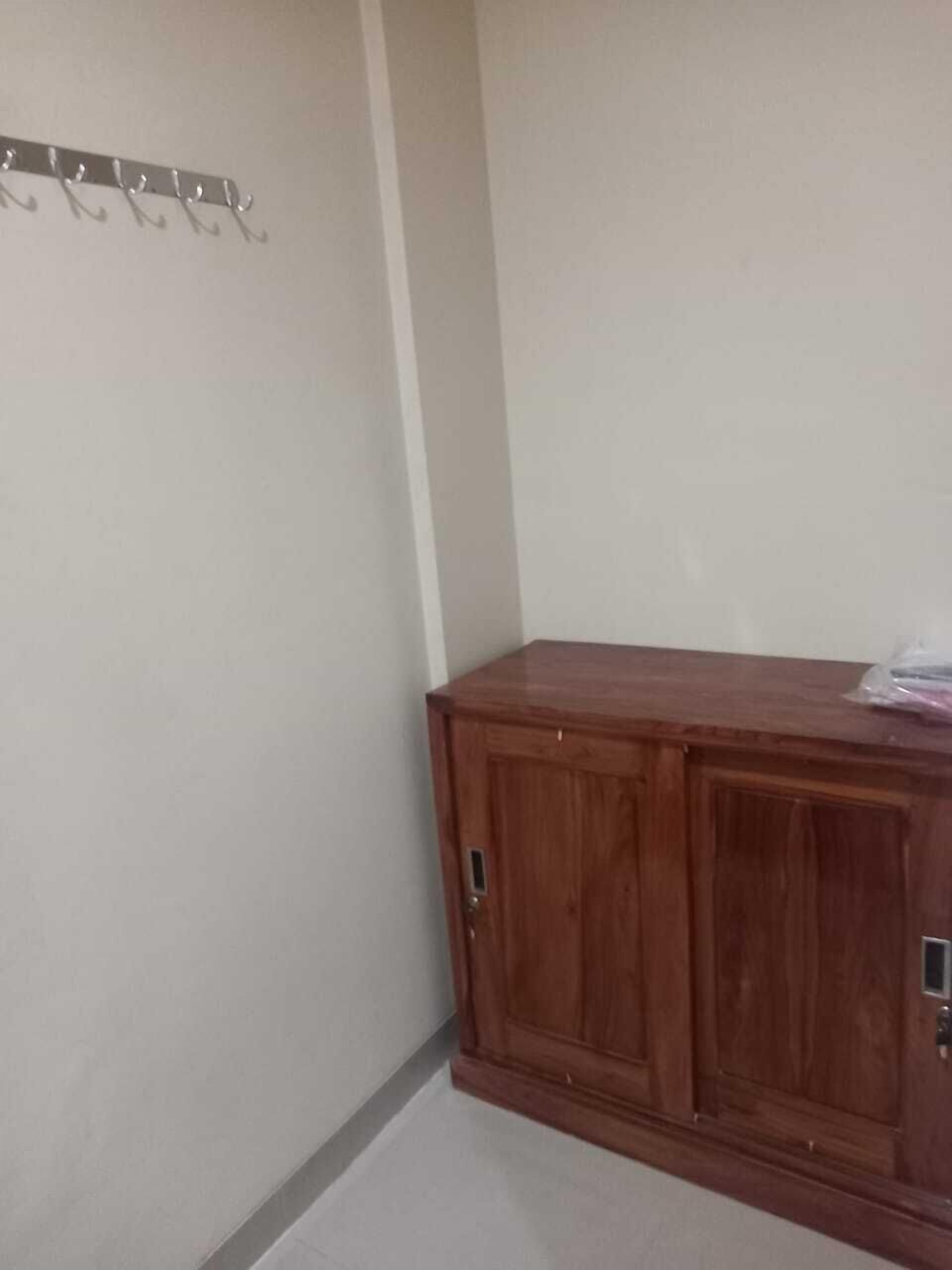 A corner room with a wooden cabinet and a coat rack.