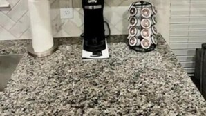 Cozinha com bancada de granito, cafeteira e chaleira.