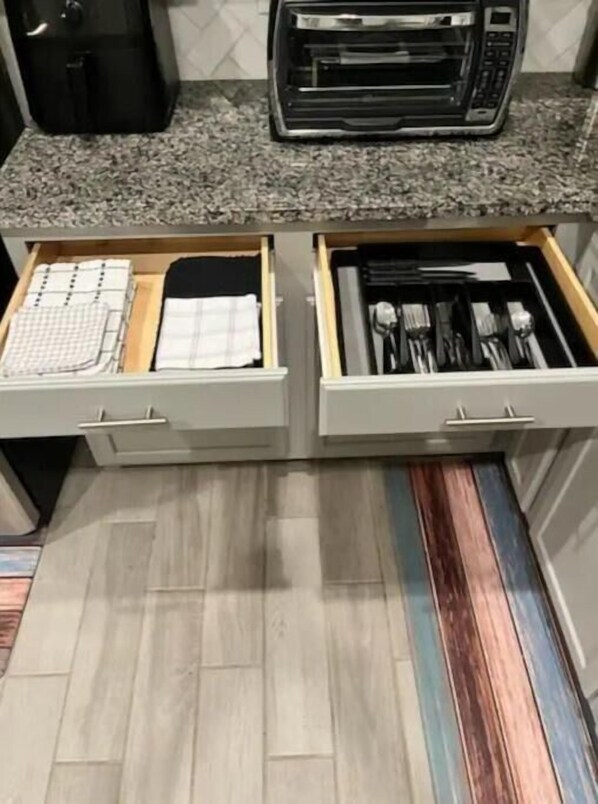 A kitchen with two drawers containing kitchen utensils and a notebook.