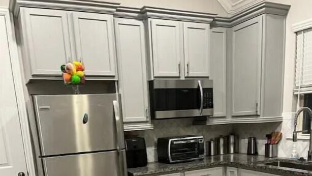 Uma cozinha com armários brancos, eletrodomésticos de aço inoxidável e um micro-ondas.